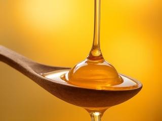 A single spoon filled with golden honey, ready to be consumed, with a soft focus background.